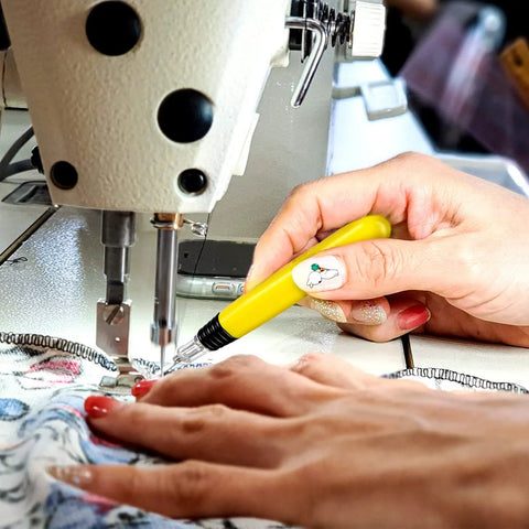 Hand using LED Needle Threader Set With Lighted Wire Loop For Sewing 2 Pack Illuminated Threading Tool near sewing machine
