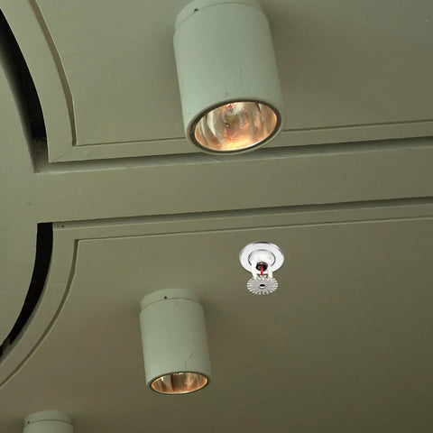 18 Pack Rock Solid Metal Fire Sprinkler Trim Rings Heavy Duty Escutcheon Plates Silver mounted on ceiling with light fixtures.