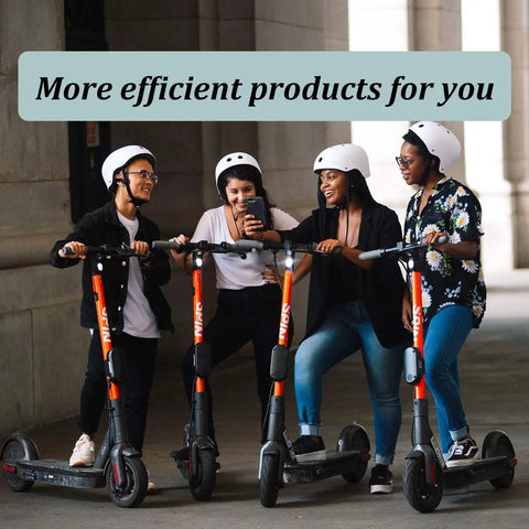 Group of people with scooters under a building archway, wearing helmets and looking at a phone.