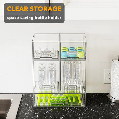 Multi Size Baby Bottle Storage Rack With Stackable Acrylic Drawers Keeps Your Counter Tight And Clutter Free Total Game Changer For Nursery Vanities Or Kitchen Cabinet Snag This Easy Access Five Pack Set. Clear acrylic unit holding baby bottles and stoppers on a black countertop.