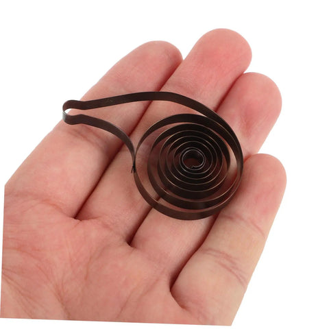 Steel Mainspring Clock Repair Kit For Mechanical Alarm Clocks 3 Pack Replacement Parts held in hand showing dark brown steel mainspring