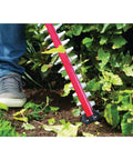 Person using Pwr Core 20 22 Inch Cordless Hedge Trimmer Kit with 2Ah battery and charger for trimming garden bushes.