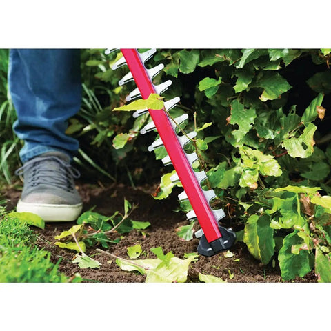 Person using Pwr Core 20 22 Inch Cordless Hedge Trimmer Kit with 2Ah battery and charger for trimming garden bushes.