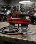 Ultra Bright E Bike Taillight With Turn Signals And Brake Sensor That Lights Up instantly For Night Riding Safety On Any Scooter Or Electric Cycle. red ABS e bike taillight with wiring and bracket on workbench