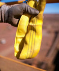 Gloved hand holding 60mm Yellow Round Sling Endless Lifting Strap, Heavy Duty 6 Foot Rigging Sling For Construction Hoisting And Moving