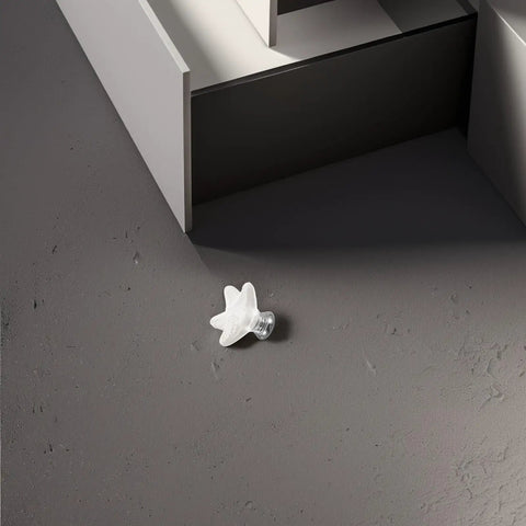 White Ceramic Star Cabinet Knob Small Decorative Drawer Pull Handle next to a cabinet on a dark floor