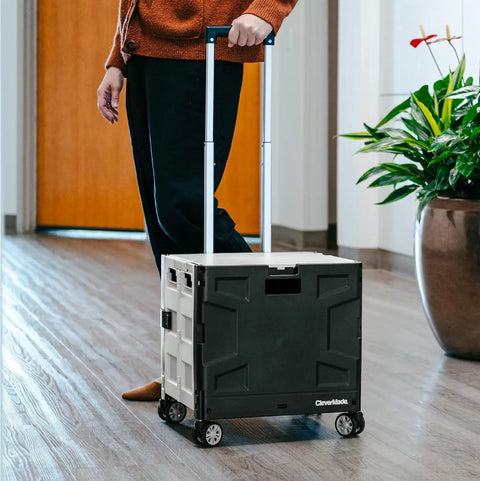 Person using black collapsible rolling cart with handle, 55L four wheel utility cart for teachers, travel, groceries and storage.