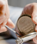 Close-up of hands using a screwdriver from the 148 Piece Automotive And Household Tool Set With Purple Case for DIY watch repair.
