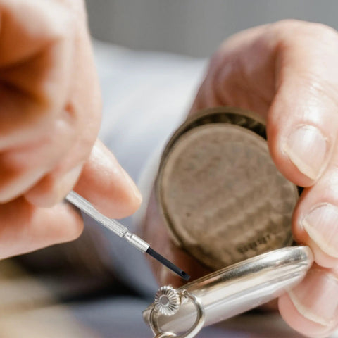Close-up of hands using a screwdriver from the 148 Piece Automotive And Household Tool Set With Purple Case for DIY watch repair.