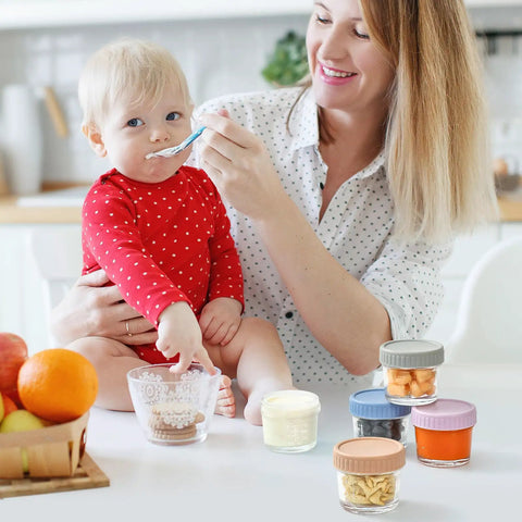 Mother feeding baby using Glass Baby Food Storage Jars 4 Oz 12 Pack With Color Lids Totally Leak Proof BPA Free Reusable Containers
