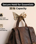 Knockout Brass Butterfly Swivel Hook Foldable Tri Arm Gold Finish Coat Rack holding a brown leather backpack, 33 lb capacity.
