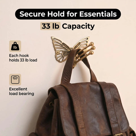 Knockout Brass Butterfly Swivel Hook Foldable Tri Arm Gold Finish Coat Rack holding a brown leather backpack, 33 lb capacity.