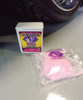 Front view of Wizards Metal Polish tin (3 oz) with a pink polishing cloth in a plastic bag beside a car wheel.