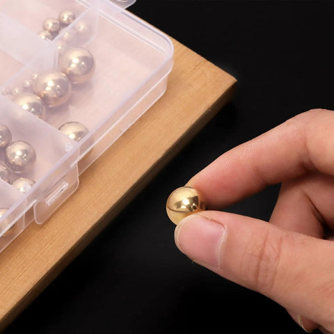 Person holding a solid brass bearing ball from the Built Tough Solid Brass Bearing Balls Assortment 160 Piece storage kit.