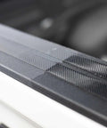Automotive exterior door-sill trim in black textured plastic, close-up view along car body.