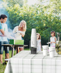 Outdoor barbecue with family using Two Tier Upright Cup And Condiment Organizer, clear acrylic dispenser on picnic table.