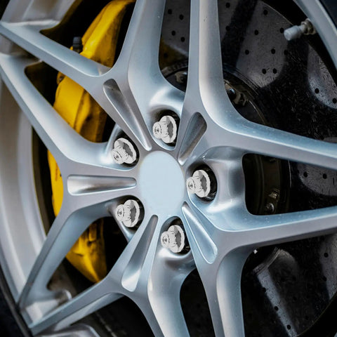 Five Piece Silver Steel Car Wheel Lug Nuts Set For Universal Tire And Rim Replacement Premium Rust Resistant Finish Bulletproof Hold No Drama Swap For Daily Drivers mounted on a silver alloy wheel with visible yellow brake caliper.