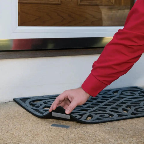 Person lifting doormat with Industrial Strength Outdoor Hook And Loop Fasteners for Extreme Weather on concrete surface