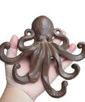 Heavy Duty Cast Iron Octopus Wall Hooks With Sleek Nautical Vibes And Aged Dark Brown Finish for hanging, in hand for size reference.