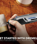 Side view of Dremel Lite cordless rotary tool engraving a metal tube; gray and black body with blue button