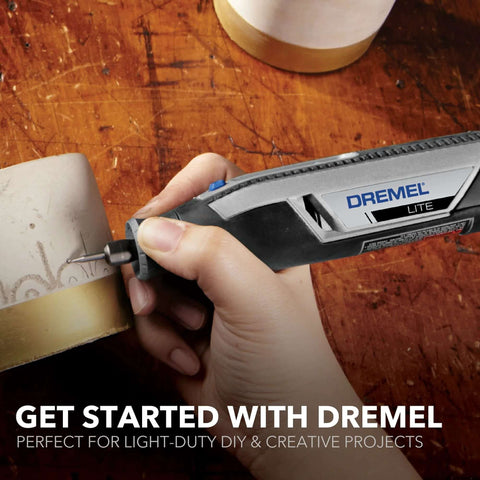 Side view of Dremel Lite cordless rotary tool engraving a metal tube; gray and black body with blue button
