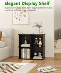 Four Cube Storage Organizer With Durable Plastic Modular Shelves in black finish, set up in a living room with decor items.