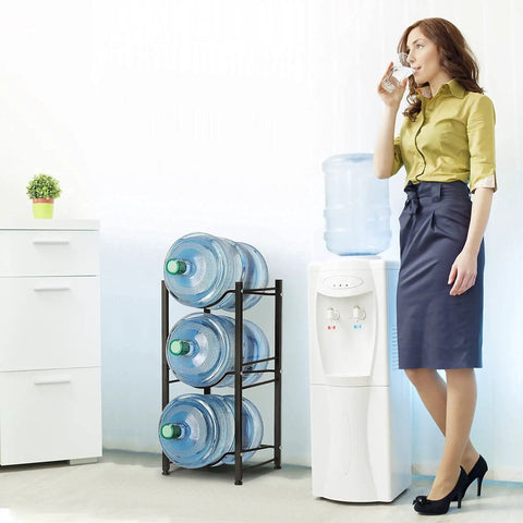 Woman standing beside Four Tier 5 Gallon Water Jug Rack Stand For Home And Office, heavy duty black bottle holder with water bottles.