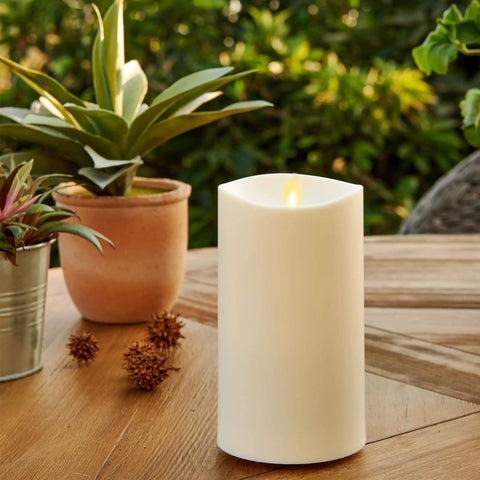 Outdoor Flameless LED Ivory Candle With Melted Edge, 3.75 x 7 Inches, Real Moving Flame on wooden table with plants