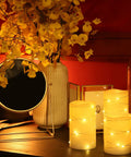 Flameless Wax Pillar Candles Set Of 3 Ivory With Embedded String Lights LED Battery Powered And 5 Hour Cycling Timer On Decorated Table