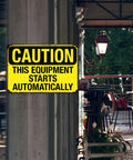 Caution sign reading 'This Equipment Starts Automatically' at workshop entrance; Warning Sign This Gear Starts Automatically Vintage Aluminum 8x12 Inch For Factory Workshop Garage Machinery Safety Management Indoor Outdoor Use Today visible.