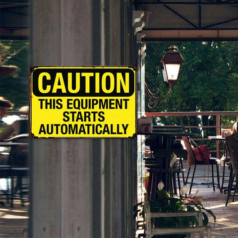 Caution sign reading 'This Equipment Starts Automatically' at workshop entrance; Warning Sign This Gear Starts Automatically Vintage Aluminum 8x12 Inch For Factory Workshop Garage Machinery Safety Management Indoor Outdoor Use Today visible.