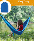 Person in a Heavy Duty Camping Hammock With 660Lb Capacity And Tree Straps Portable Outdoor Hammock Tent near a river with storage bag inset.