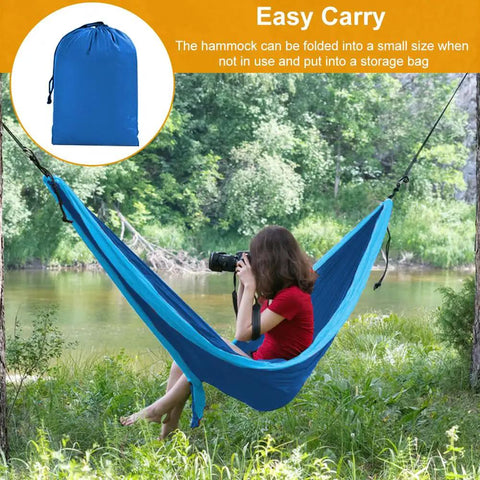 Person in a Heavy Duty Camping Hammock With 660Lb Capacity And Tree Straps Portable Outdoor Hammock Tent near a river with storage bag inset.