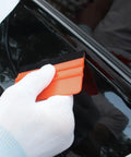 Gloved hand using squeegee from All-In-One Vinyl Wrap Heat Gun Kit For Cars And Window Tinting, 1800W 110V Hot Air Tool with Squeegees