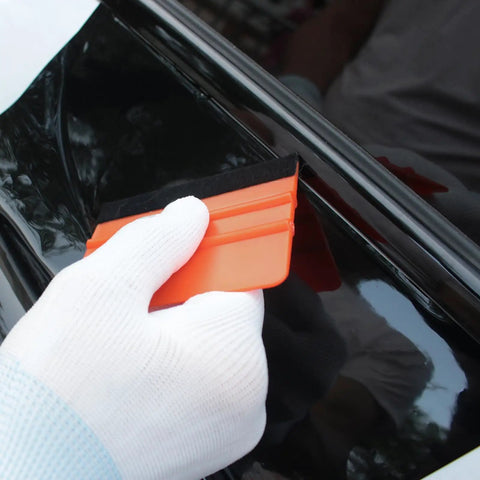 Gloved hand using squeegee from All-In-One Vinyl Wrap Heat Gun Kit For Cars And Window Tinting, 1800W 110V Hot Air Tool with Squeegees