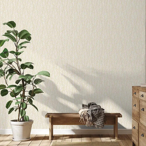 Room with removable peel and stick wallpaper featuring beige block print leaves on off white, wooden furniture, and plant decor.