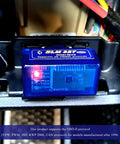 ELM327 OBDII Car Diagnostic Scanner With Bluetooth Pro Auto Code Reader installed in a vehicle's OBD2 port, red LED lit