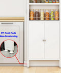 White floor-standing cabinet with shelves, jars, and PP foot pads for non-scratching close-up, placed by a kitchen cabinet.