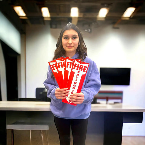 Woman holding Four Pack Fire Extinguisher Signs For Office And Warehouse Safety, Durable 80 Mil Thick Plastic, OSHA Compliant