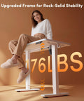 Woman sitting on 32 Inch Electric Standing Desk With Adjustable Height From Sitting To Standing, showcasing desk stability at 176 lbs