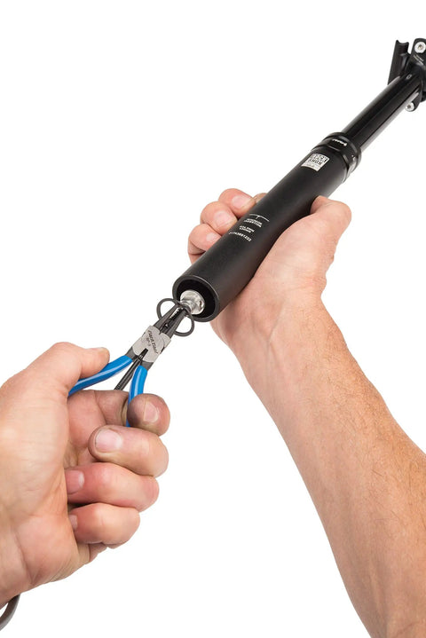 Pro Grade Snap Ring Pliers Set RPSET-2 in use with blue handles, gripping a ring from a cylindrical object.
