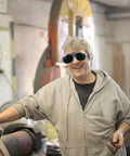 Man wearing Badass Welding Glasses With Anti Glare Black And Gray Lenses in workshop, smiling and working on projects.