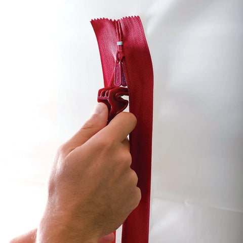 Hand using Heavy Duty Dust Barrier Zipper 2 Pack Self Adhesive Entry Door For Remodeling Jobs Red HDAZ2 on white material.