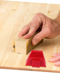 Hand holding sandpaper on a wood plank with red 12 Piece Modular Wrench Organizer Tray For Workbenches Garages And DIY Projects Durable Plastic Tool Holder nearby.