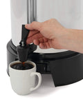 Person pouring coffee from Heavy Duty Commercial Coffee Urn With 55 Cup Capacity And Automatic Temperature Control into a cup
