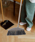 Dark Grey Angle Floor Broom With Long Stainless Steel Handle And Dense Stiff Bristles snags pet hair and kitchen messes.