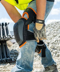 Heavy Duty Hinged Knee Pads With Gel Foam Cushioning For All Day Comfort And Stability Large Protective Surface For Easy Side To Side Movement Secure Quick Fasten Buckle And Adjustable Thigh Strap Black on person at construction site.