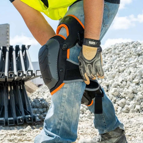 Heavy Duty Hinged Knee Pads With Gel Foam Cushioning For All Day Comfort And Stability Large Protective Surface For Easy Side To Side Movement Secure Quick Fasten Buckle And Adjustable Thigh Strap Black on person at construction site.