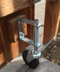 Installed Beefed Up 4 Inch Gate Caster Wheel Set With Spring Loaded Swivel on wooden gate, showcasing rugged rubber and steel build.