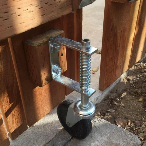 Installed Beefed Up 4 Inch Gate Caster Wheel Set With Spring Loaded Swivel on wooden gate, showcasing rugged rubber and steel build.